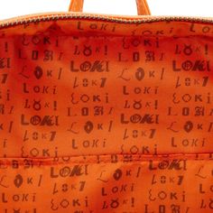 an orange handbag with lots of writing on the front and side, sitting in front of a white background