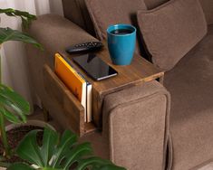 a coffee table with a book, remote control and cell phone on it next to a couch