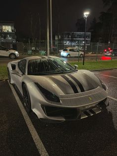 a silver and black sports car parked in a parking lot next to a street light