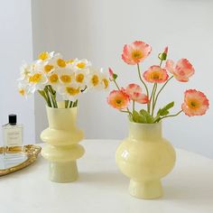 two vases with flowers in them sitting on a table