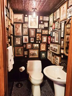 a toilet and sink in a small room with many pictures on the wall above it