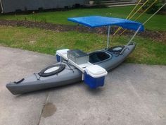 a gray and blue boat sitting on top of a cement ground next to a house