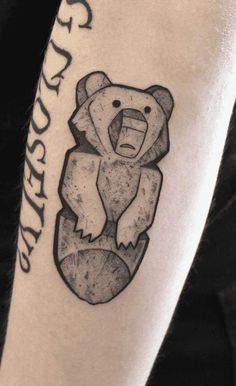 a black and white photo of a bear tattoo on the right arm with words written below it