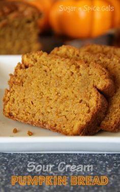 two pieces of pumpkin bread on a white plate with oranges in the background and text that reads sour cream pumpkin bread