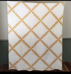 an orange and white quilt hanging on a wall