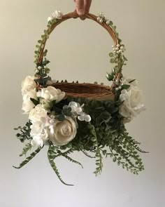 a basket with flowers and greenery hanging from it