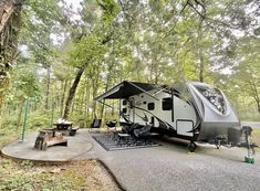 an rv is parked in the woods next to a picnic table