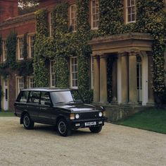 a black suv parked in front of a large building with ivy growing on it's walls