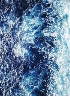 the ocean is blue and white with waves coming in from it's surface, as seen from above