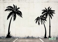 two palm trees are painted on the side of a concrete wall in an empty parking lot