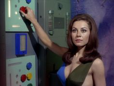 a woman in a green dress standing next to a wall with magnets on it