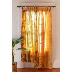 a yellow curtain hanging on the side of a wall next to a potted plant