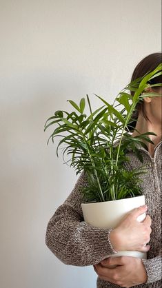 a woman holding a plant in a white bowl