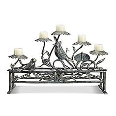 a candle holder with birds on it and four candles in front of the top one