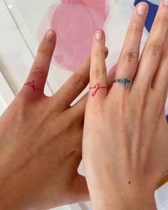 two hands holding each other with tattoos on their fingers and the word love written in red ink