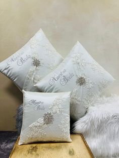 three white pillows sitting on top of a wooden table next to a furnishing