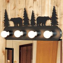 a bathroom mirror with three lights on it and two bears in the woods behind it