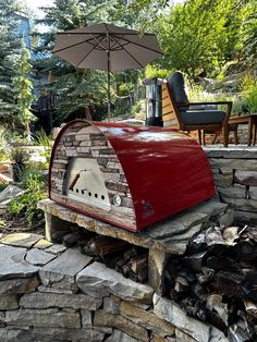 a red mailbox sitting on top of a pile of wood next to an umbrella