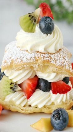 a pastry topped with whipped cream, kiwis and blueberries on top of it