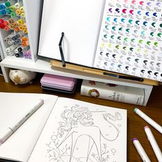 an open book on a desk with markers and pens