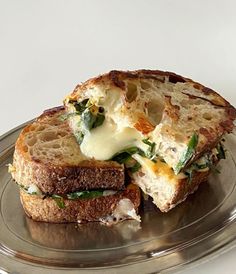 a grilled cheese sandwich with spinach and melted cheese on it sitting on a silver plate