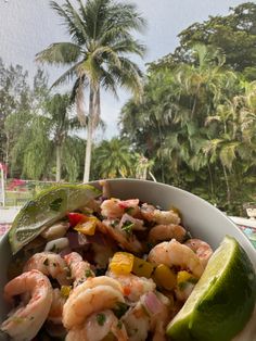 a bowl filled with shrimp and vegetables on top of a table next to a pool