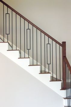 a cat sitting on top of a wooden banister next to a white wall