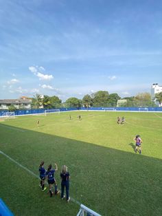 a group of people standing on top of a field next to a soccer ball court