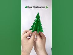 two hands holding up a paper christmas tree with the words paper christmas trees on it