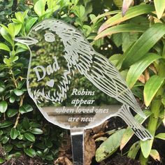 a glass bird sitting on top of a metal stand in front of some bushes and trees