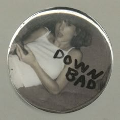 a button with the words down bad on it and a woman holding a cell phone