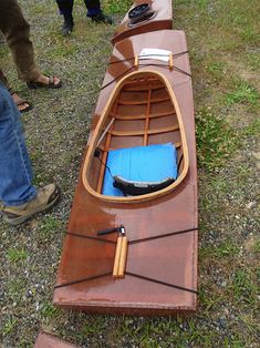 a wooden canoe sitting on top of a grass covered field