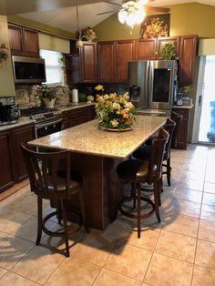 a kitchen island with four stools in the middle and flowers on top, sitting next to an oven