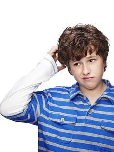 a young boy is holding his head with one hand and looking at the camera while wearing a blue striped shirt