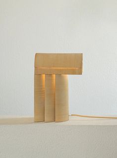 a wooden lamp sitting on top of a white table next to a wall and floor