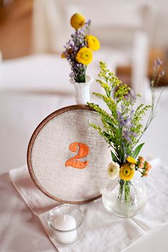 two vases filled with flowers sitting on top of a white table cloth covered table