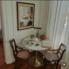 a small table with two chairs and a book on it in front of a window