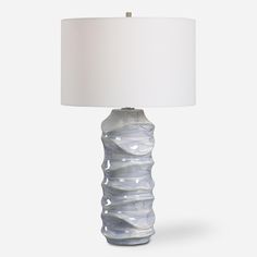 a glass lamp with a white shade on it's base and a light in the shape of a wave