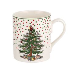 a white coffee mug with a christmas tree on the front and polka dots around it