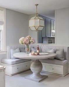 a white table with some flowers on top of it and a bench in the middle