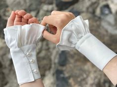 two hands holding each other while wearing white gloves