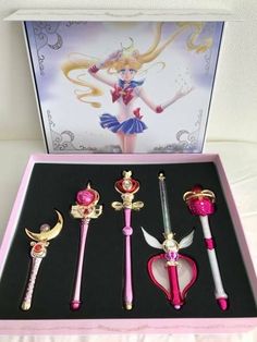 four different types of sailor moon wands in a pink box on a white surface