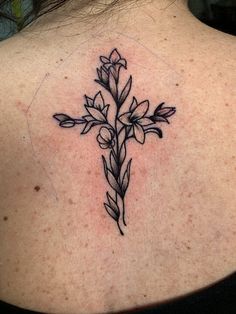 a woman with a cross tattoo on her back shoulder and behind her neck is a flower