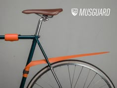 an orange and blue bicycle parked against a wall