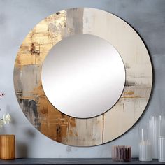 a round mirror sitting on top of a table next to a vase with flowers in it