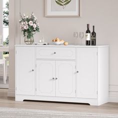 a white sideboard with wine glasses and bottles on it in a living room setting