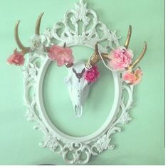 there is a deer skull with flowers in the frame on the wall next to a pair of shoes