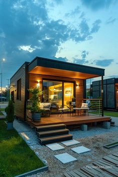 a small house with a deck and lights on it's side, in the evening