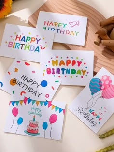 happy birthday cards with balloons and confetti on a table next to flowers, cinnamons and candles