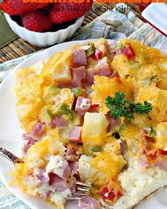 an omelet with ham, cheese and vegetables is on a plate next to strawberries